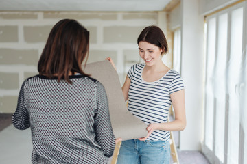 Two woman discussing a roll of wallpaper
