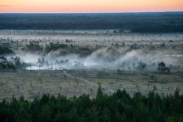 misty and cloudy sunrise above green fields and forests