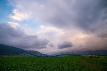 misty and cloudy sunrise above green fields and forests