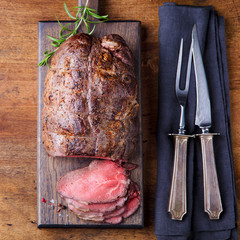 Roast beef on cutting board. Wooden background. Top view.
