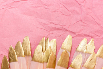 Pink and gold feathers on a pink background