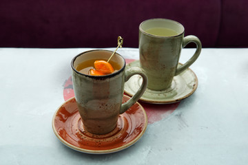 Two cups of tea: citrus tea with mango and orange slices and ginger hot tea in a Japanese cafe.