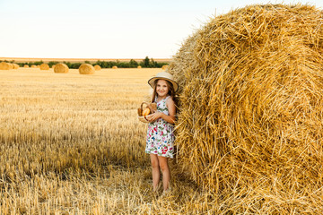 Adorable girl in rye field on sunset with a basket of bread.