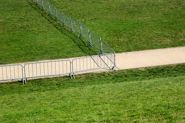 A footpath on green grass behind movable metal fence