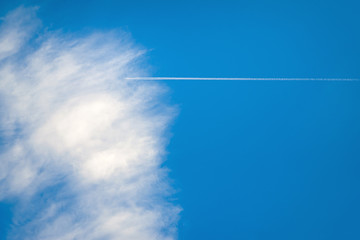 Blue sky with white clouds and jet trail.
