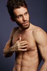 Fototapeta premium pensive fitness model with hand on his breast posing to the camera. close up side view photo.