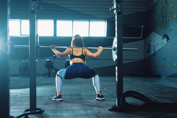 Gymnast girl doing squat barbell.  Front view of attractive young woman