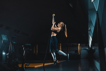Fototapeta na wymiar Full length wide angle shot of a woman performing rope climbs at the gym. Copyspace background with athletics healthy composition. Crossfit and fitness