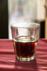 A beautifully backlit glass of red soft drink on a restaurant table