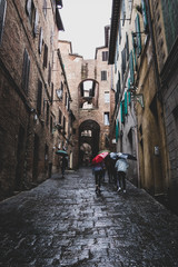 Streets with Arches and people with umbrellas. Siena, Tuscany