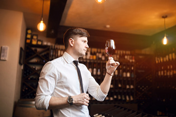 handsome man holding glass and looking through it. close up side view photo.