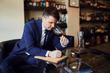young elegant man with a glasss in his hand writing structure, texture and balance of wine. copy space