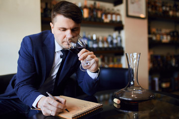 good looking sommelier runs a business. man procures wine list that matches with cuisine. close up...