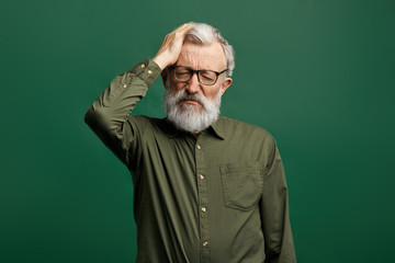 attractive old man in green T-shirt suffering from headache, intracranial pressure.close up...