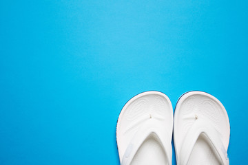 Flip flops on a blue isolated background. White female flip flops.