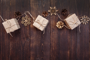 Christmas greetings card. Kraft gift boxes with rope and snowflakes, bumps on a wooden background with place for your text