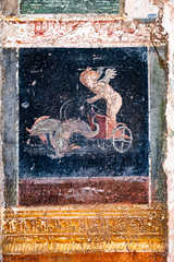 Winged Amorino leads a fish-drawn chariot, a figure of divinity of ancient Rome in Pompeii.