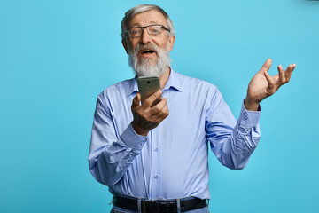 Old man raised hand holding mobile phone, making phone call, senior man uses gadget witjot...