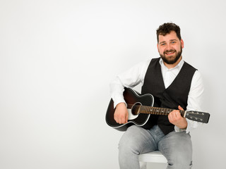 man with black hair and beard playing and singing with acoustic guitar on white background and is happy