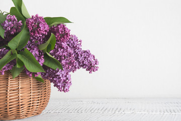 Basket of lilac flower on white wooden background. Vintage toned. Mothers and womens day.