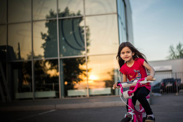 beautiful girl riding her bike on sunset background