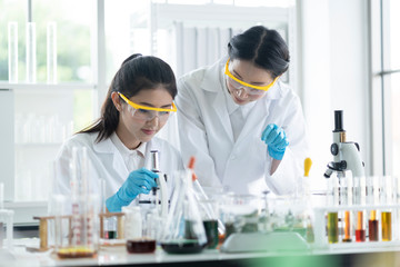 Female  scientists are preparing microscopes for testing and analysis through an extension to find the results of medical research. Scientific and chemical concepts