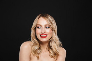 Happy cheerful blonde woman with bright makeup red lips posing isolated over black wall background.