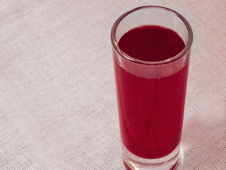 Glass with red drink stay on white fabric tablecloth. Juice, wine or soft beverage image