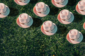 Summer background Pink sunhat on green grass. Pop art, creative summer party concept. Minimalism.