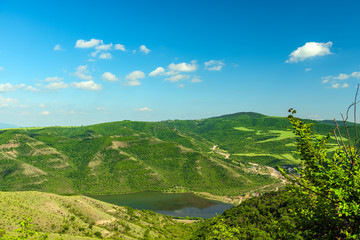 Landscape of mountains covered with green forest and blue sky with clouds 