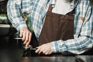 Image of european barista man making coffee while working in cafe or coffeehouse outdoor
