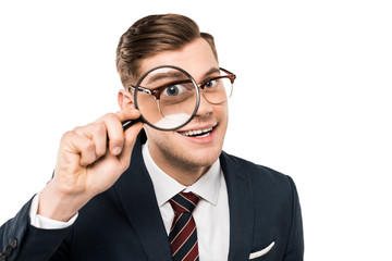 happy businessman holding magnifying glass near eye isolated on white