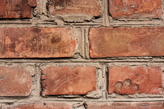Brick wall fragment. Old dirty orange and red bricks with defects. Grunge texture with cracks and weathered