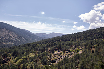 Fototapeta na wymiar Panoramic of some mountains under a cloudy blue sky