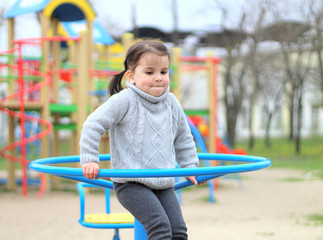child rides on the carousel in the playground
