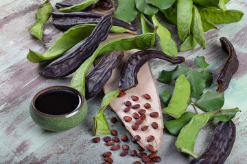 Carob bean(Harnup). Healthy organic sweet carob pods with seeds and leaves on wooden background.