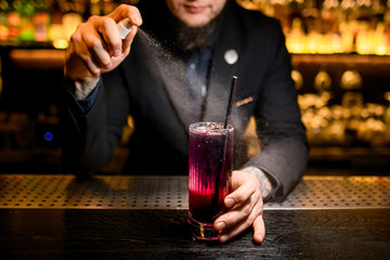 Close-up of bartender spraying to alcohol cocktail