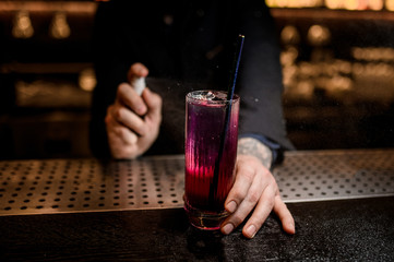 Close shot of bartender spraying on alcohol cocktail