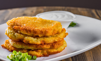 potato pancakes with sour cream in a plate on wooden table
