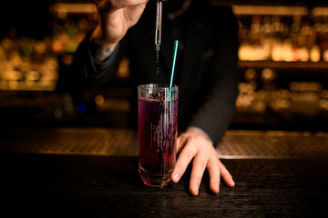 Bartender using dropper to make a cocktail