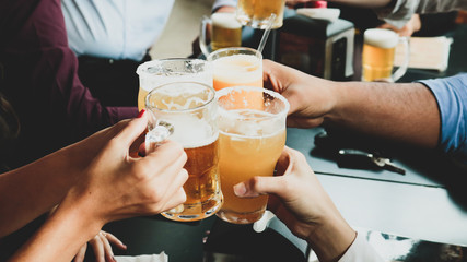 People at a bar toasting and drinking beer, juice and wine