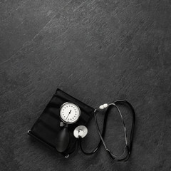 Blood pressure meter and stethoscope from above on dark stone background with  space for notes,...