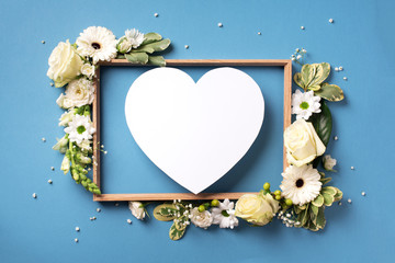 Frame of white flowers, paper heart over blue background. Valentines day, Woman day concept. Spring...