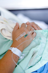 The saline solution of the patient's hand was lying in bed in a medical room. 