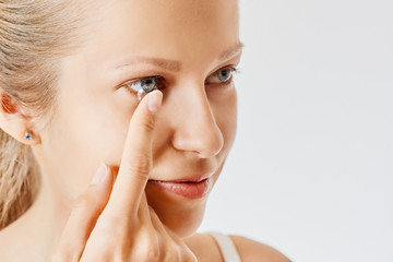 Young woman puts contact lens in her eye. Eyewear, eyesight and vision, eye care and health,...