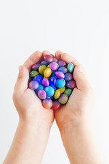 Fototapeta na wymiar Multicolored candies in the hands of a child on a white isolated background