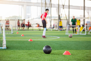 Obraz na płótnie Canvas black football on green artificial turf with mini goal and blurry soccer team training,