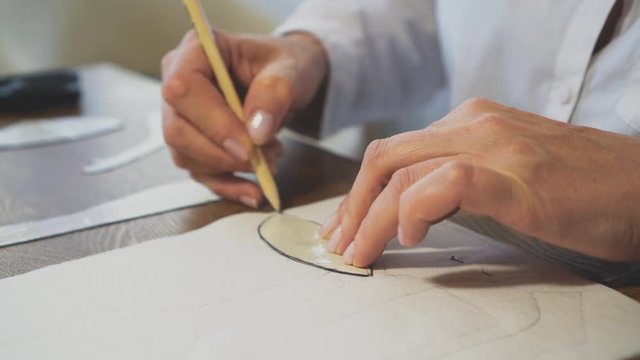 Woman tailor making mockups with pencil.
