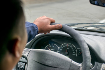 Car speedometer and driver's hand on the steering wheel.