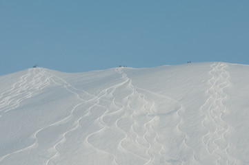 Three snowboard groups standing on the mountain top and getting ready for dropping in front of the sliding down traces